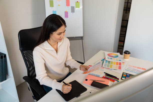 istock Creative woman designer brainstorming color ideas on tablet while surrounded by swatches in her office 2205034070