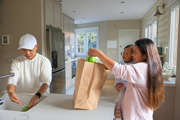 istock Young family unpacking groceries together in modern kitchen 2205034201