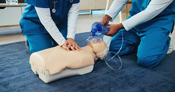 istock Mask, medical or nurses learning cpr on mannequin for first aid, help cardiac arrest or safety protocol. Healthcare class, hands or people with respiratory tool in paramedic course or nursing school 2205034347