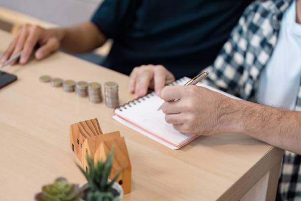 LGBTQ couple working together on a savings plan for their future home, documenting financial goals and strategies.