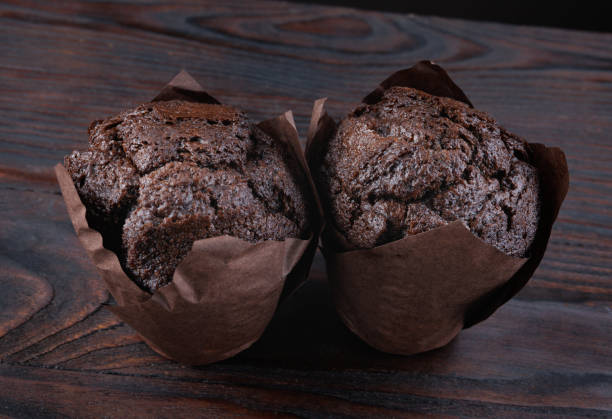 istock Two chocolate muffins on a wooden surface. Muffin in a paper cup. 2205035884