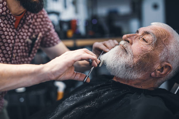 Senior man cutting his beard in barbershop