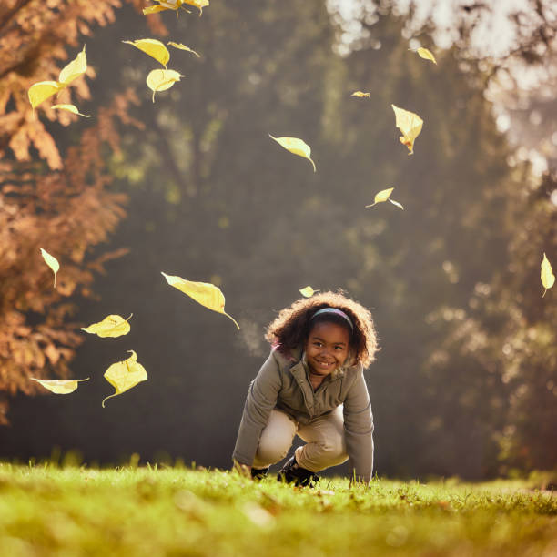 Happy African American girl having fun while playing in autumn day at the park. Copy space.