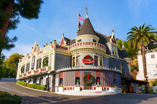Los Angeles, California - December 24, 2024: The Magic Castle in Los Angeles displaying Christmas decorations and American flags, surrounded by lush greenery and a clear blue sky.