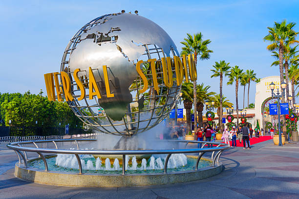 Los Angeles, California - December 24, 2024: Universal Studios iconic globe fountain at the entrance in Los Angeles, surrounded by palm trees and holiday decorations.