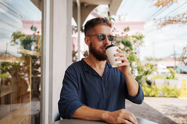 istock Young Man Enjoying Coffee at a Trendy Caf 2205042803