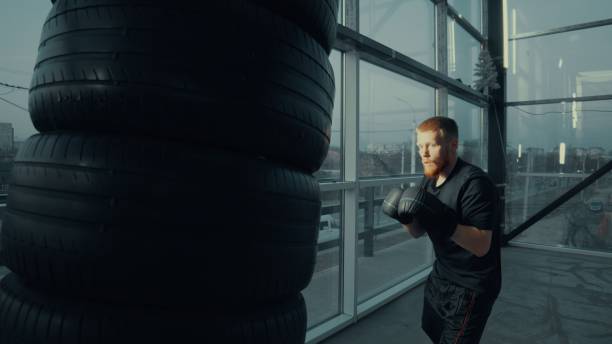 istock Young athlete practicing boxing punches on a tire training bag 2205044337