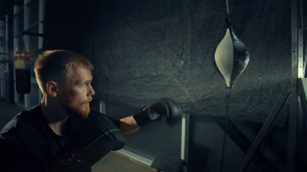istock Boxer training with punching bag, improving his boxing skills 2205044349