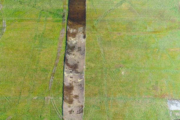 rectangular trench excavated in a field for the preparation of a construction site, aerial top view with a drone