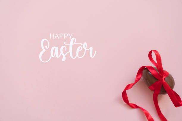 Sweet chocolate egg with bow on pink background, top view. Space for text