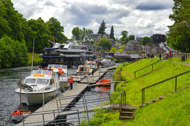 A small yacht motors along a river navigating between the riverbanks in Scotland