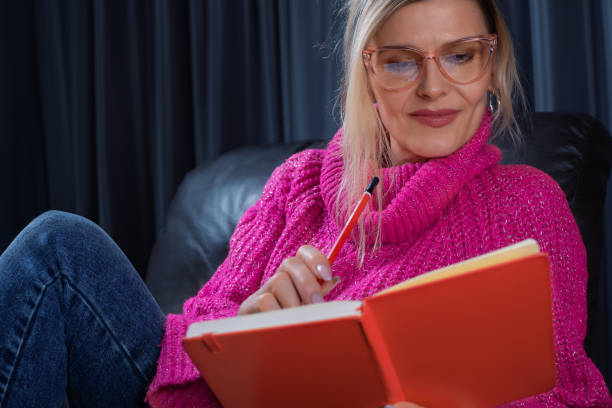 istock Woman relaxing on armchair reading notes in a notebook and thinking about plans 2205053792