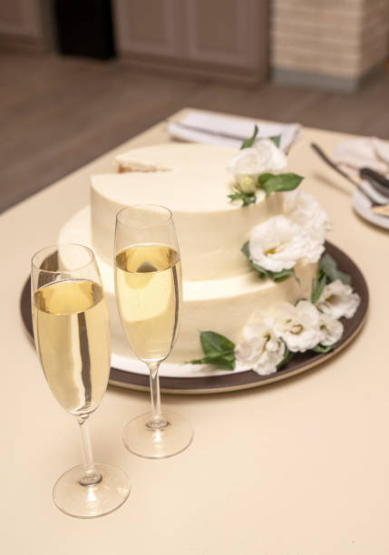 istock Two champagne glasses on the table with a cake 2205053868