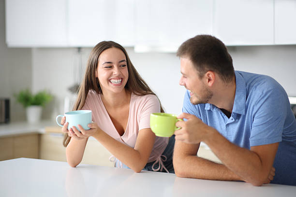 istock Funny couple drinking and talking in the kitchen 2205054407