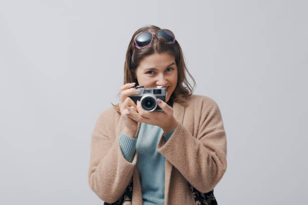 Happy woman using a vintage analog film camera, isolated on white background
