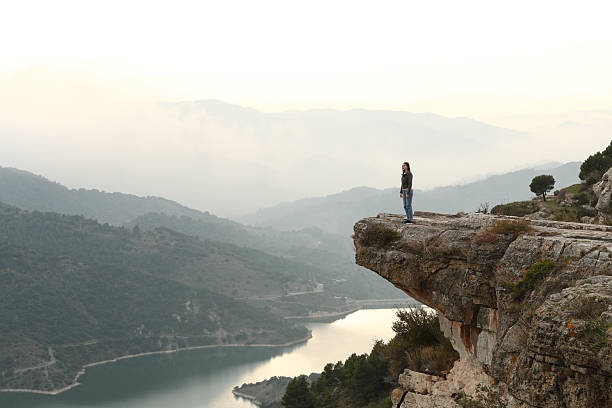 istock Woman standing in a cliff contemplating nature 2205054718