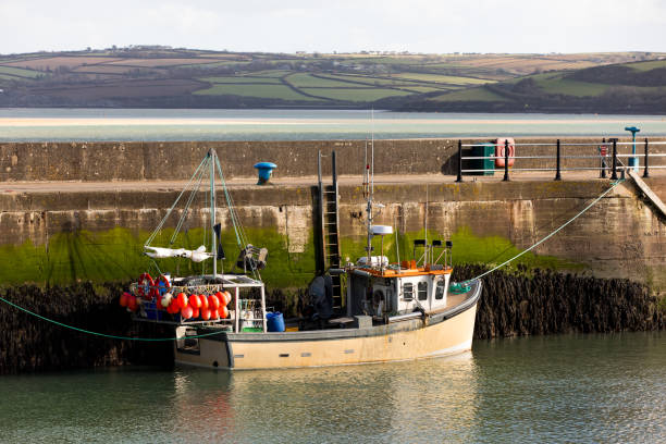 A fishing boat alongside the harbour wall.  The Camel estuary on the background.