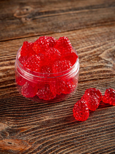 istock Raspberry-shaped sweets in a clear glass jar. Brown wooden background. 2205063169