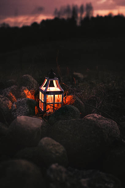istock Rustic Lantern with a Burning Candle Among Rocks at Dusk 2205063677