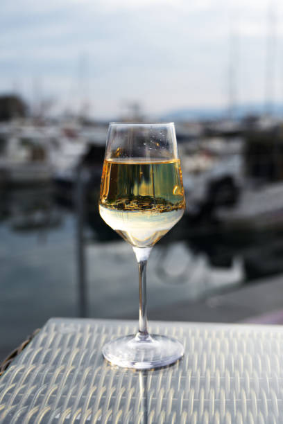 istock A glass of white wine rests on a textured table, with a blurred marina backdrop 2205064856