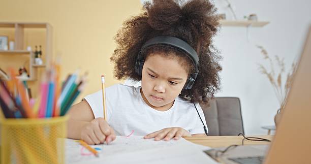 istock A focused child is diligently studying at home, wearing headphones while immersed in learning 2205065797