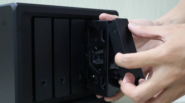 istock close up of someone's hand inserting a hard disk into a Network Attached Storage 2205068505