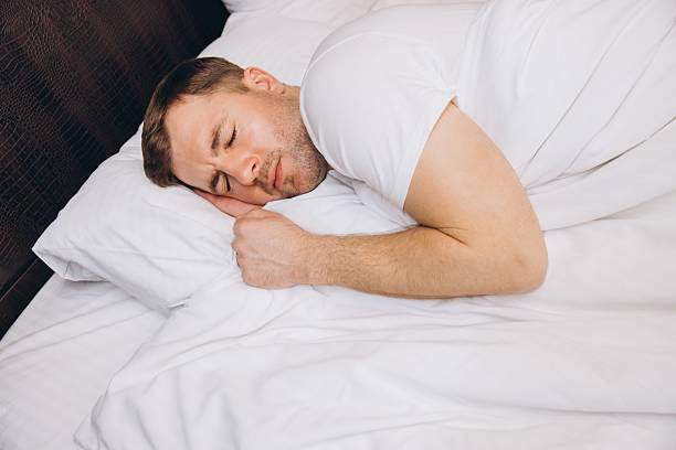 istock Man sleeping peacefully in bed enjoying good night sleep 2205071475