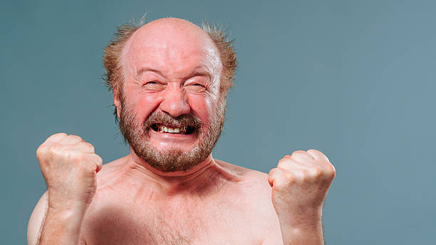 istock Cheerful man celebrates with raised fists in a simple background 2205073341