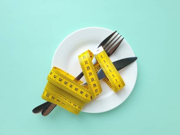 istock Fork and knife wrapped in measuring tape 2205073410