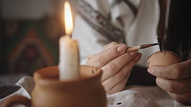 istock An Artisan Skillfully Decorating an Egg with the Soft Glow of Candlelight in a Cozy Setting 2205074452