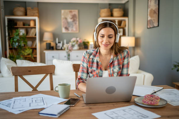 istock Architect working from home on a laptop and wearing headphones 2205074538