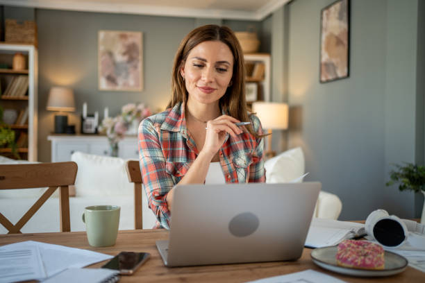 istock Focused woman working from home on laptop at dining table 2205074703