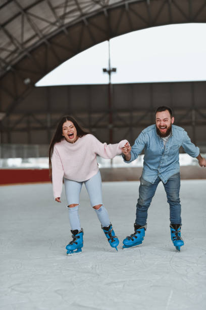istock Cheerful Couple Unable to Control Laughing While Ice Skating Holding Hands 2205079981