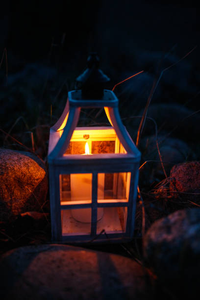 istock Close-up of a Glowing Candle in a Rustic Lantern Among Rocks at Night 2205081663
