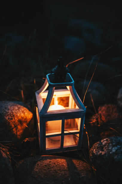 istock Close-up of a Glowing Candle in a Rustic Lantern Among Rocks at Night 2205081732