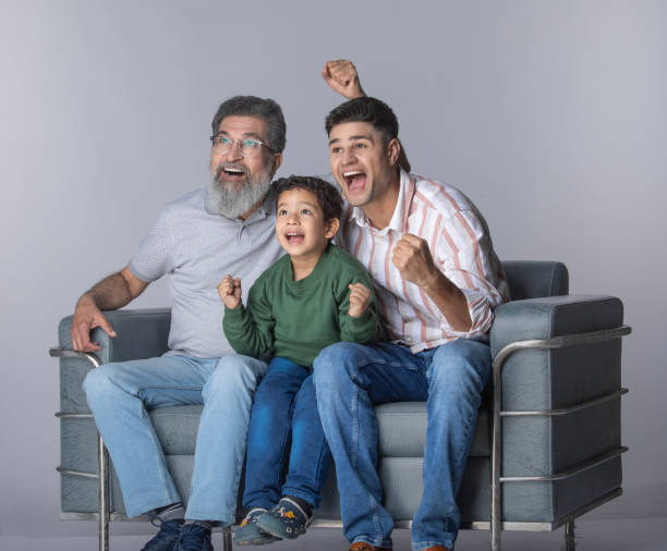 istock Three generations of males watch match on white background 2205081763