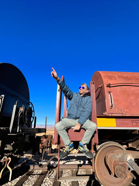 istock Man pointing at the sky while sitting on a train wagon along Route 66 in Arizona 2205084603