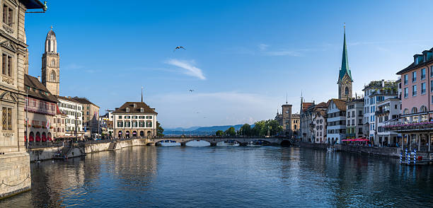 Scenic panorama of Zurich’s historic old town with iconic church towers, traditional buildings, and the Limmat River under a clear sky.