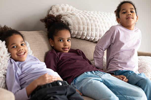 istock Three happy sisters lounging on a couch, engaged with a smartphone 2205085392