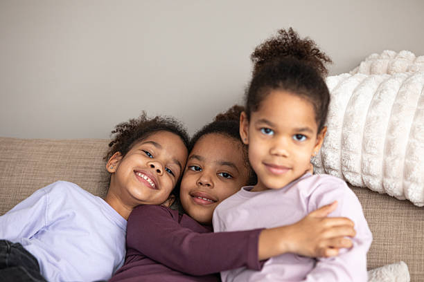 istock Three happy sisters lounging on a couch, engaged with a smartphone 2205086189