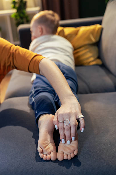 istock Mother holding son's feet while relaxing on sofa at home 2205087481