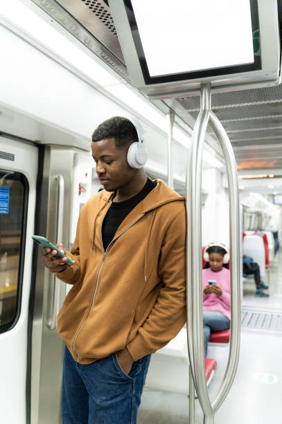 istock Young man using smartphone and listening music on subway train 2205090157