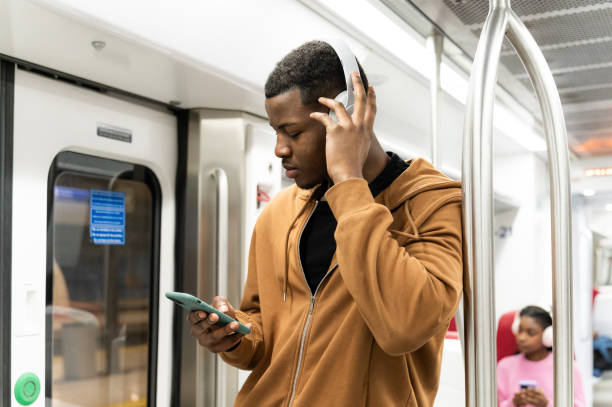 Commuter enjoying music on a smartphone while traveling on a subway train, surrounded by the hustle of urban life and modern technology
