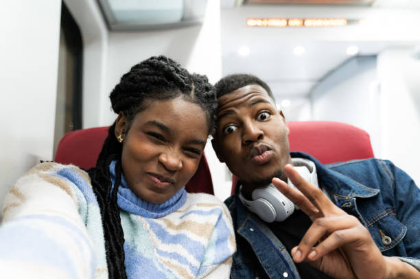 Two young students are taking a selfie on a train, making funny faces and enjoying their journey