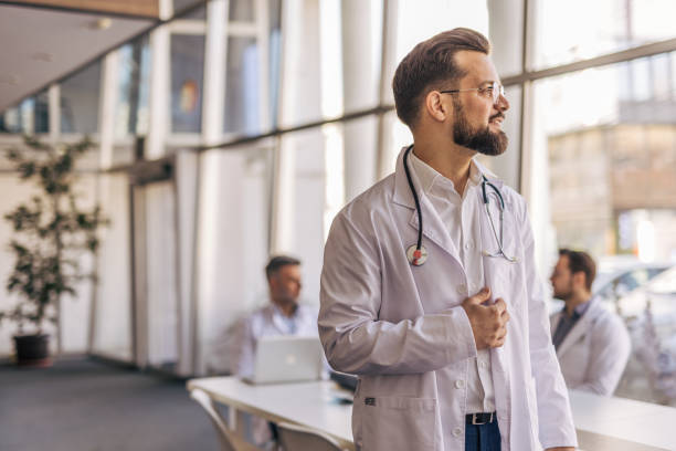 istock Young doctor looking out window in hospital lobby 2205091476