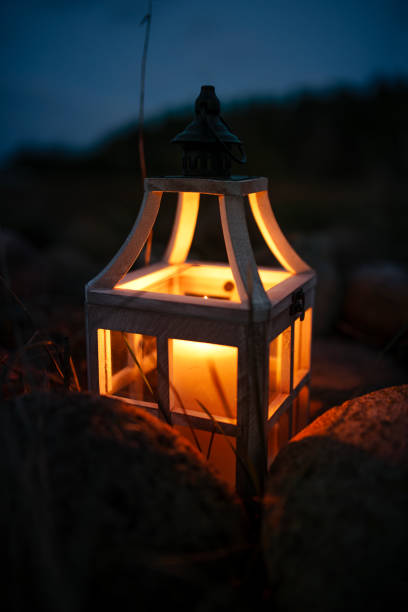 istock Close-up of a Glowing Candle in a Rustic Lantern Among Rocks at Night 2205091572