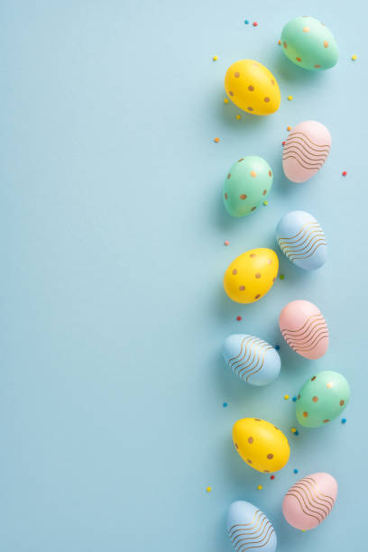 istock Easter vertical eggs in vibrant pastel colors and patterns arranged on a light green surface 2205091810
