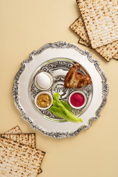 istock Passover vertical Seder plate displaying symbolic foods with matzos around, symbolizing the Jewish holiday. Elements include parsley, egg, shank bone and horseradish, representing important traditions 2205091828