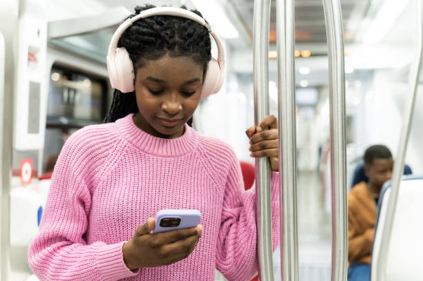 istock Young student using smartphone and listening music on subway train 2205092593