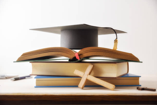 istock Religious studies and graduate with books Bible and mortarboard isolated 2205092952